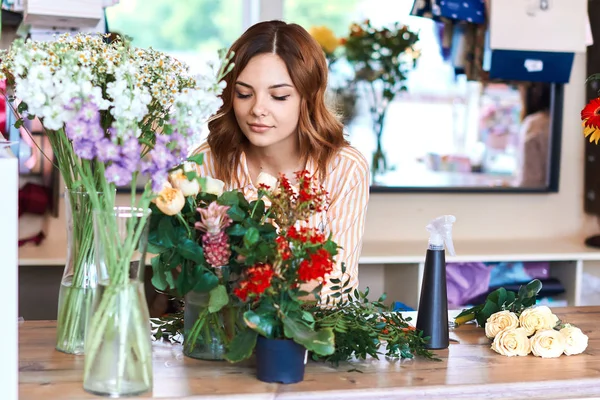 female florist looking at flowers, choosing for bouquet in flower shop