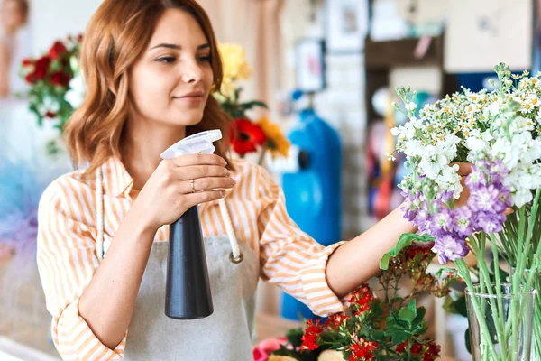 Gember mooie vrouw zorgt voor bloemen — Stockfoto