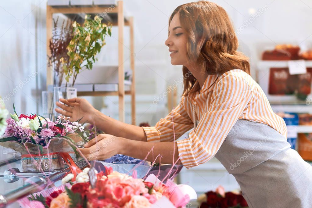 young pleasant florist enjoying the beauty of her flowers