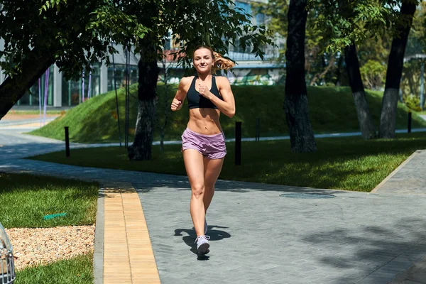 Young strong slim girl running in the park