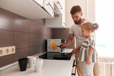 yakışıklı baba ve onun sevimli kızı mutfakta krep hazırlanıyor.