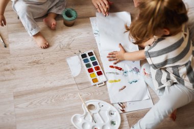 küçük sevimli çocuk çizer. parmak boyaları, el izleri