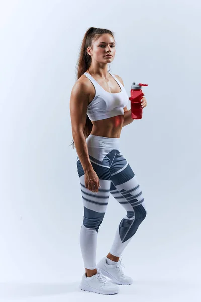 Tired young slim woman holding a bottle of water — Stock Photo, Image