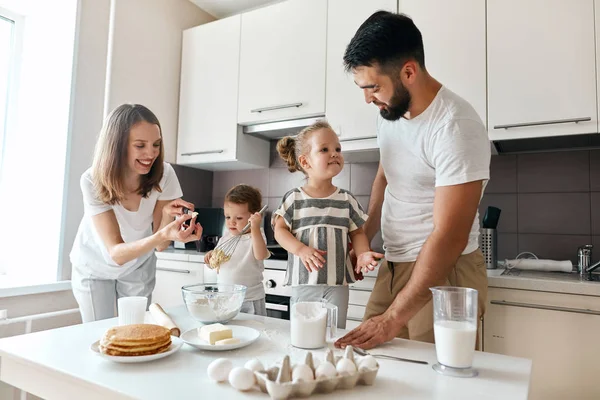 Young happy man and woman spending time with kids in the kitchen room — Stock Photo, Image