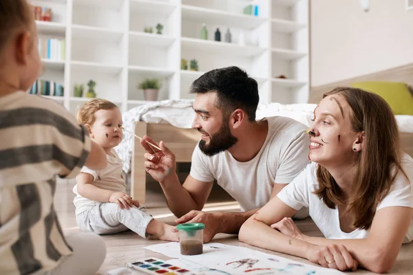 Funny bearded daddy painting his babys nose with black color — Stock Photo, Image