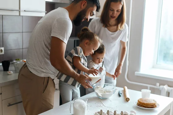 Unida jovem família preparando bolo de aniversário caseiro — Fotografia de Stock