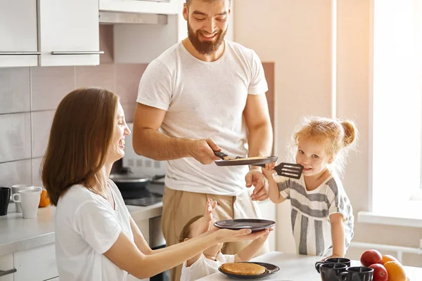 Young cheerful daddy tossing pancakes in the kitchen — Stock Photo, Image