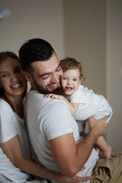 Cheerful daddy and mommy hugging their kid — Stock Photo, Image