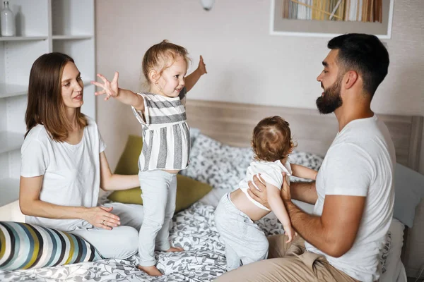 Positieve ouders en kinderen die plezier hebben en springen op het bed. — Stockfoto