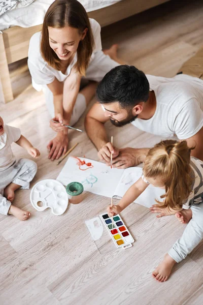 Vidám fiatal család és gyermekük gyakorló festés — Stock Fotó