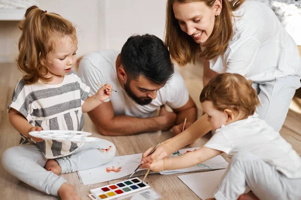 Fröhliches Paar und ihre entzückende Tochter malen in Aquarellen — Stockfoto