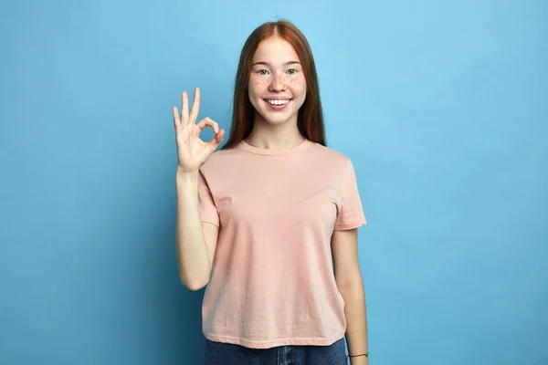 Positive female student with freckles showing ok sign with fingers — Stock Photo, Image