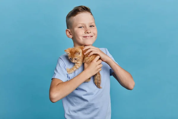 Garoto positivo abraçando seu gatinho laranja — Fotografia de Stock