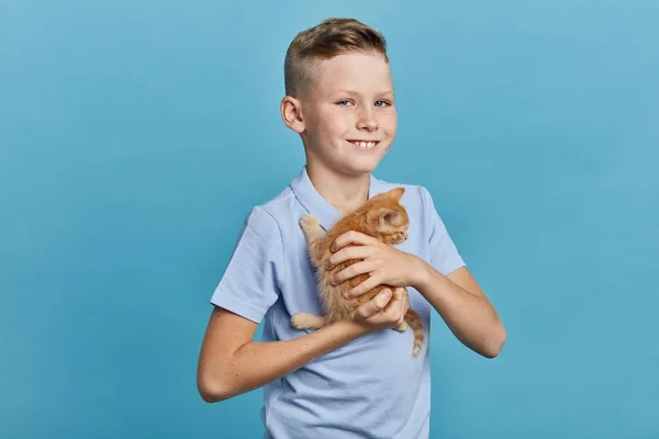 Jovem sorrindo tipo amigável menino segurando um gatinho — Fotografia de Stock