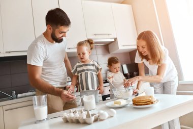 Neşeli anne ve baba hafta sonları çocuklarla yemek yapmayı seviyor.