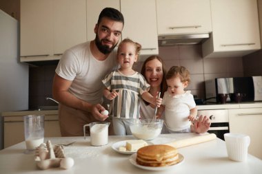 İyi görünümlü genç bir aile mutfak masasının arkasında duruyor.