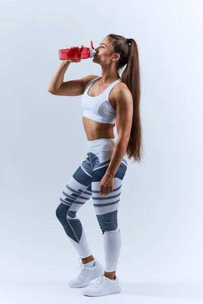Dobrze zbudowana brunetka kobieta pije zimną wodę po treningu w centrum sportowym — Zdjęcie stockowe