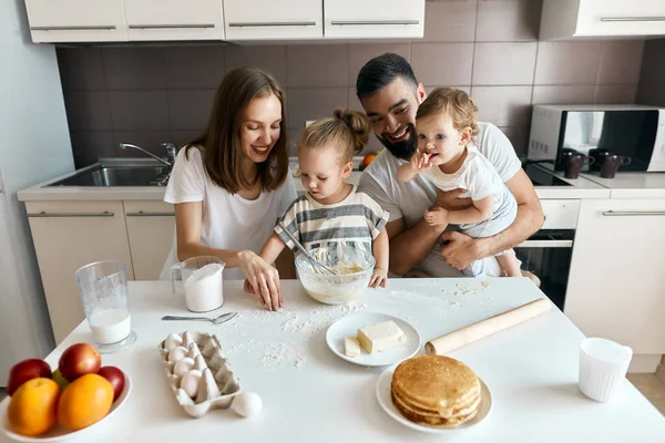 Funny family with dirty faces picking flour which is luing on the table — Stock Photo, Image