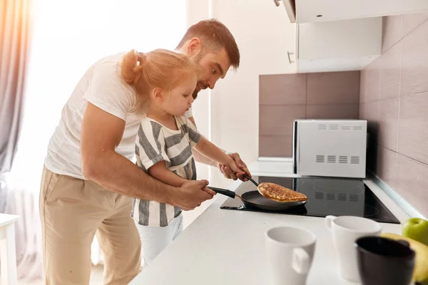 Young father and his beautiful blonde daughter enjoying cooking pancakes — Stock Photo, Image