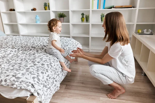 Gyönyörű anya és imádnivaló baba játszik a hálószobában — Stock Fotó