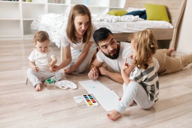 Neşeli ebeveynler çocuklarına resim yapmayı öğretiyor. Eğitim.