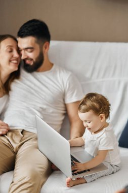 Bebekleri dizüstü bilgisayarın önünde otururken sevgi dolu bir çift sarılıyor.