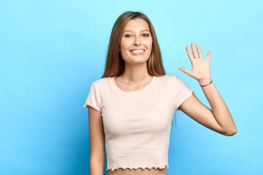 Sevecen, sevimli, genç bir bayan el sallıyor kameraya.