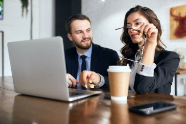Yakışıklı, neşeli bir adam elinde gözlük olan güzel bir kadına bakıyor.