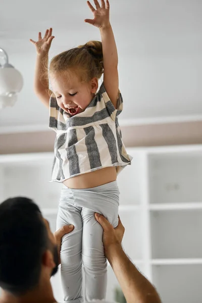 young daddy lifting daughter indoors