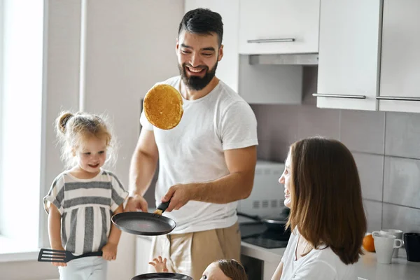 Bearded happy father showing tricks with pancakes in the kitchen — Stock Photo, Image