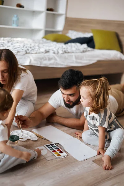 Family and their children using brushes to paint a card for granny on her birthday — Stock Fotó