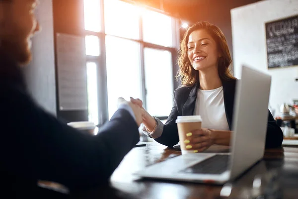 Two positive business people shaking hands indoors