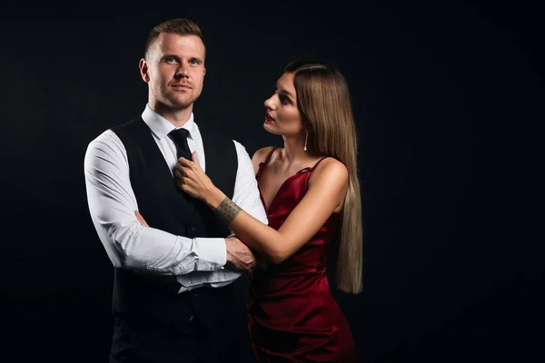 Mujer rubia de moda con el pelo largo y liso ayudando a su hombre con una corbata —  Fotos de Stock