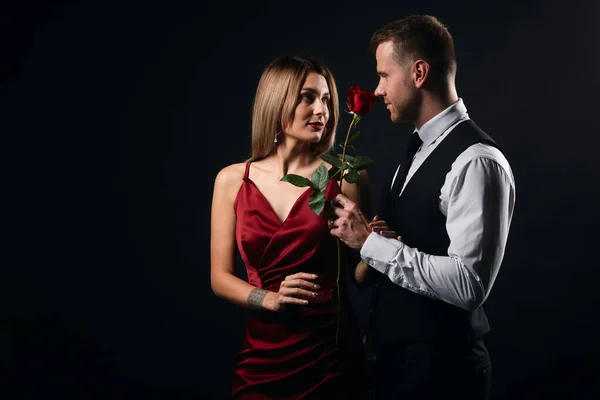 Encantadora mujer rubia en vestido rojo de moda que tiene una cita con una rosa —  Fotos de Stock