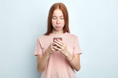 Beyaz arka planda izole edilmiş akıllı telefon kullanan hoşnutsuz, gücenmiş bir kadın.