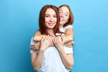 Mutlu kızıl kız histerisinin arkasında duruyor ve ona sarılıyor.