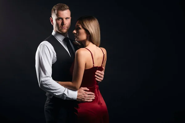 Porträt eines jungen Modepaares, das sich anschaut, während der Mann die Frau umarmt — Stockfoto