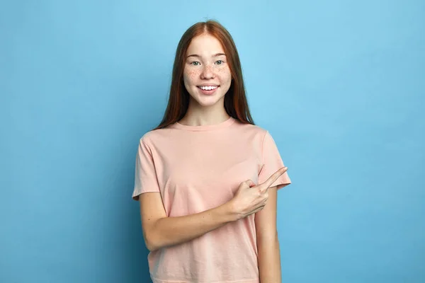 Ragazza sorridente in T-shirt puntando il dito verso lo spazio copia — Foto Stock