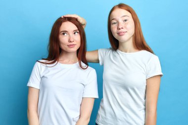 Zencefilli abla küçük kız kardeşinin başını tutuyor.