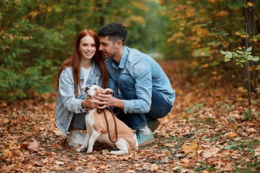 Güzel görünüşlü, neşeli çift köpekle hafta sonunun tadını çıkarıyor.