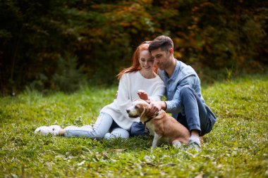 Mutlu çift çimen okşayan köpek üzerinde dinleniyor.