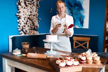 İki kozalak tutan kadın, pastayı süslemek için birini seçiyor.