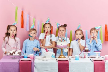 Parti boynuzlarıyla kameraya bakan bir grup mutlu çocuk.
