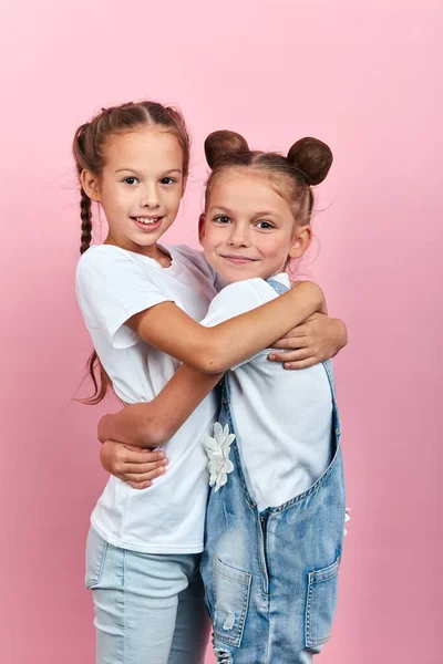 Cute two friends hugging in the studio with pink wall — Stock Photo, Image