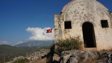 Türk bayrağı hayalet şehir Kayaköy uçan. Fethiye, Türkiye.