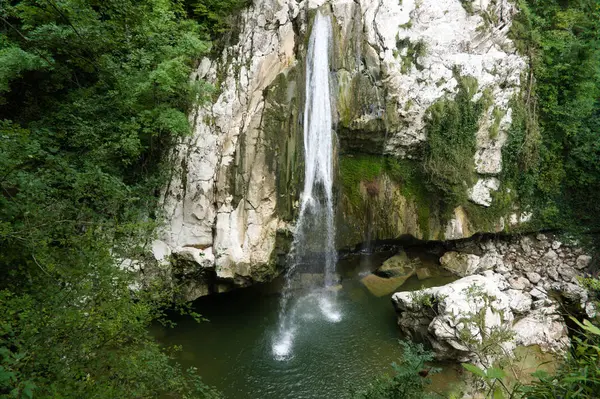 Водопад в трещине между скалами за деревьями. Водопады Агура — стоковое фото