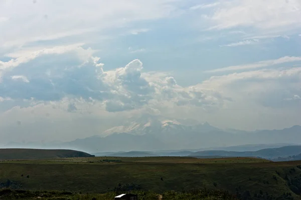 Gumbashi pass green lawn landscape with the highest mountain of europe mount elbrus on the horizon