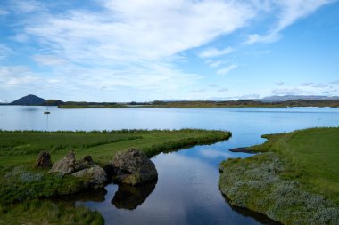 Myvatn Gölü, İzlanda 'da güneşli bir gün. Volkanik bir gölün mavi sularında yansıyan bulutlar..