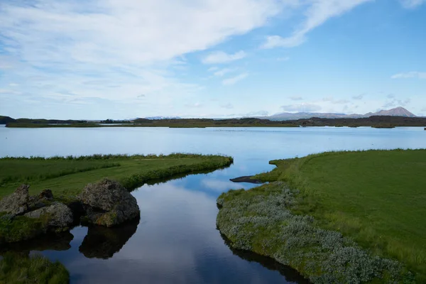Myvatn Gölü, İzlanda 'da güneşli bir gün. Volkanik bir gölün mavi sularında yansıyan bulutlar..