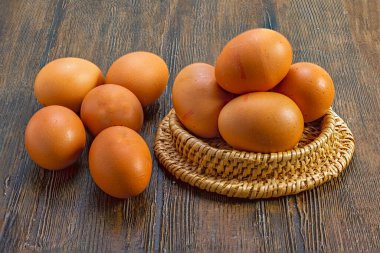 Kırsal ahşap masada hasır sepetin içinde taze kahverengi yumurtalar.